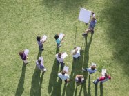 Businessman leading meeting at flipchart in sunny field — Stock Photo