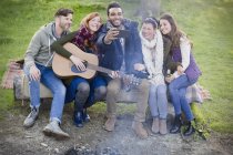 Amigos con guitarra tomando selfie con el teléfono de la cámara en el camping - foto de stock