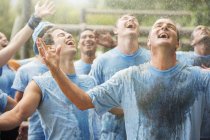 Équipe enthousiaste profitant de la pluie au camp d'entraînement — Photo de stock