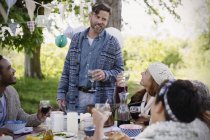 Uomo brindare amici al tavolo della festa in giardino — Foto stock