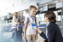 Бортпроводник разговаривает с ребенком-путешественником в аэропорту — стоковое фото