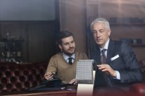 Tailor and businessman browsing fabric in menswear shop — Stock Photo