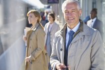 Ritratto uomo d'affari sorridente sulla piattaforma della stazione ferroviaria soleggiata — Foto stock