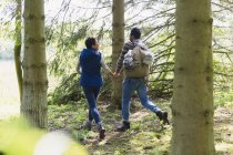 Couple holding hands and hiking with backpack in woods — Stock Photo