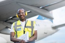 Air traffic controller with clipboard under airplane on airport tarmac — Stock Photo