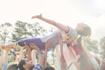 Carefree woman crowdsurfing supported by team — Stock Photo