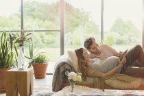 Embarazada pareja que pone utilizando tableta digital en la sala de estar - foto de stock