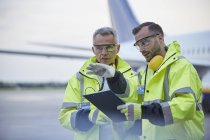 Operai di terra addetti al controllo del traffico aereo con appunti che parlano sull'asfalto dell'aeroporto — Foto stock