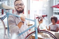 Smiling man carrying bicycle in cafe — Stock Photo