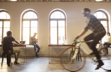 Gelegenheitsunternehmer fährt Fahrrad im Großraumbüro — Stockfoto