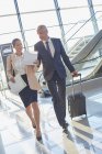 Geschäftsleute diskutieren über Papierkram beim Kofferziehen am Flughafen — Stockfoto