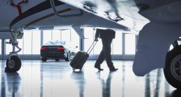 Businessman pulling suitcase outside corporate jet — Stock Photo