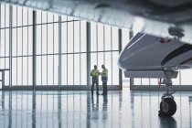 Air traffic control ground crew workers talking in airplane hangar — Stock Photo
