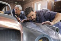 Mechaniker begutachtet Oldtimer in Autowerkstatt — Stockfoto