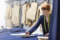 Tecido de corte de alfaiate feminino na oficina de moda masculina — Fotografia de Stock