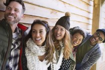 Smiling friends standing in a row outside cabin — Stock Photo