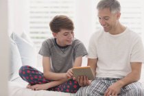 Батько і син в піжамі, використовуючи цифровий планшет — стокове фото