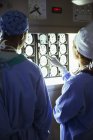 Cirujanos revisando y discutiendo resonancias magnéticas en clínica médica - foto de stock