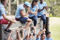 Cheering team at wall on boot camp obstacle course — Stock Photo