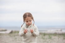 Neugieriges Mädchen untersucht Kieselsteine am Strand — Stockfoto