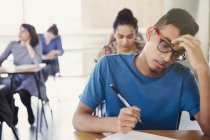 Серйозна студентка коледжу проходить тест за столом у класі — стокове фото