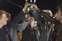 Junge Männer stoßen auf Party mit Bierflaschen an — Stockfoto