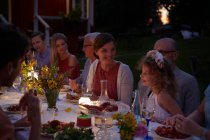 Семья наслаждается ужином при свечах в патио ночью — стоковое фото