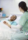 Infermiera che tiene i pazienti sorridenti mano nella stanza d'ospedale — Foto stock