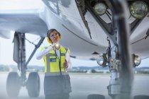 Travailleur au sol sous l'avion avec lampe de poche sur l'aire de trafic de l'aéroport — Photo de stock