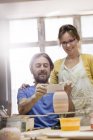 Couple d'âge mûr photographiant vase de poterie avec téléphone caméra en studio — Photo de stock