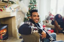 Portrait homme souriant profitant de Noël dans le salon — Photo de stock