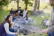 Freunde hängen am Lagerfeuer herum und spielen Gitarre — Stockfoto