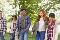 Smiling friends walking in park — Stock Photo