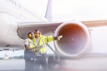 Air traffic control ground crew workers talking near airplane on airport tarmac — Stock Photo