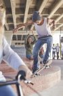 Друзі дивляться підлітковий хлопчик скейтбординг на скейтборді в парку — стокове фото