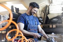 Smiling metal worker using equipment in workshop — Stock Photo
