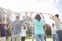 Team forming connected circle with plastic hoop in sunny field — Stock Photo