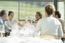 Freunde stoßen in sonnigem Restaurant auf Weingläser an — Stockfoto