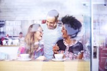 Friends laughing and drinking coffee in cafe — Stock Photo