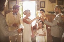 Молодая пара и гости тосты с шампанским во время свадебного приема в домашнем номере — стоковое фото