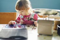 Neugieriges kleines Mädchen mit digitalem Tablet — Stockfoto