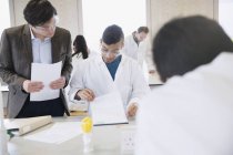 Professeur de sciences aidant un étudiant dans une salle de classe de laboratoire de sciences — Photo de stock