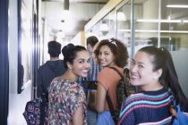 Portrait smiling female college students walking in corridor — Stock Photo