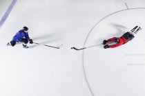 Overhead ver jugadores de hockey buceo para disco en el hielo - foto de stock