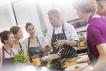 Students listening to chef teacher in cooking class kitchen — Stock Photo