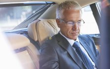 Businessman riding in back seat of town car — Stock Photo