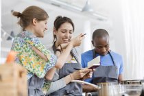 Women tasting food in cooking class kitchen — Stock Photo