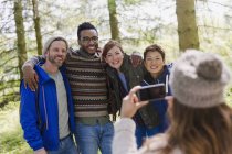 Woman with camera phone photographing friends hiking in woods — Stock Photo