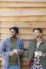 Smiling men drinking coffee outside cabin — Stock Photo