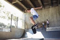 Adolescente ragazzo flipping skateboard a skate park — Foto stock